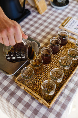 Pouring coffee out of a carafe into tasting glasses