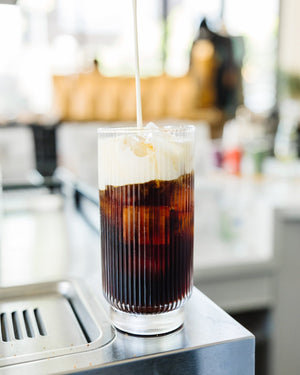 Cold Brew Coffee in a glass with cold foam being poured on top
