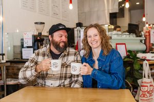 Ragamuffin Coffee owners, Sarah and Shawn Pritchett smiling holding mugs of coffee