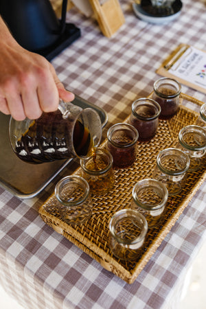 pouring coffee out of carafe into little jars for a tasting