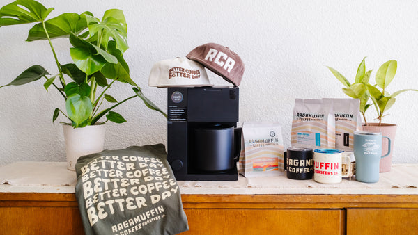 Home coffee brewing setup with Ragamuffin Coffee Roasters essentials including fresh coffee, mugs, and merch gifts.