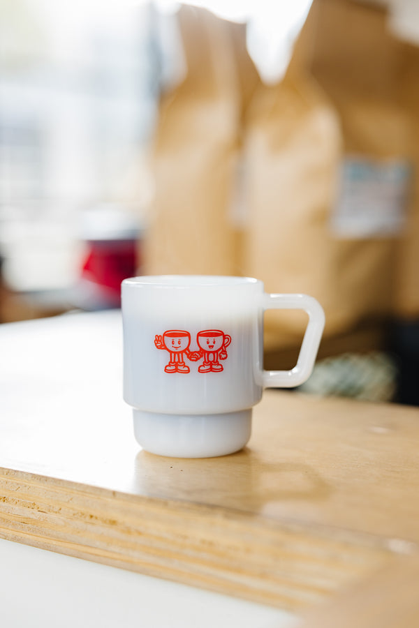 White milk glass espresso cup with red coffee cup people holding hands