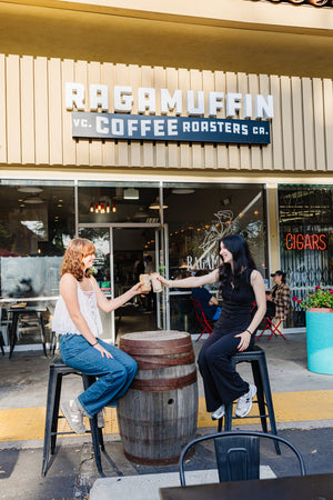 Two girls cheering coffee drinks in front of Ragamuffin Coffee