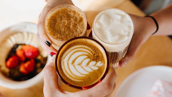 a collection of lattes coming together in a cheers at Ragamuffin Coffee shop